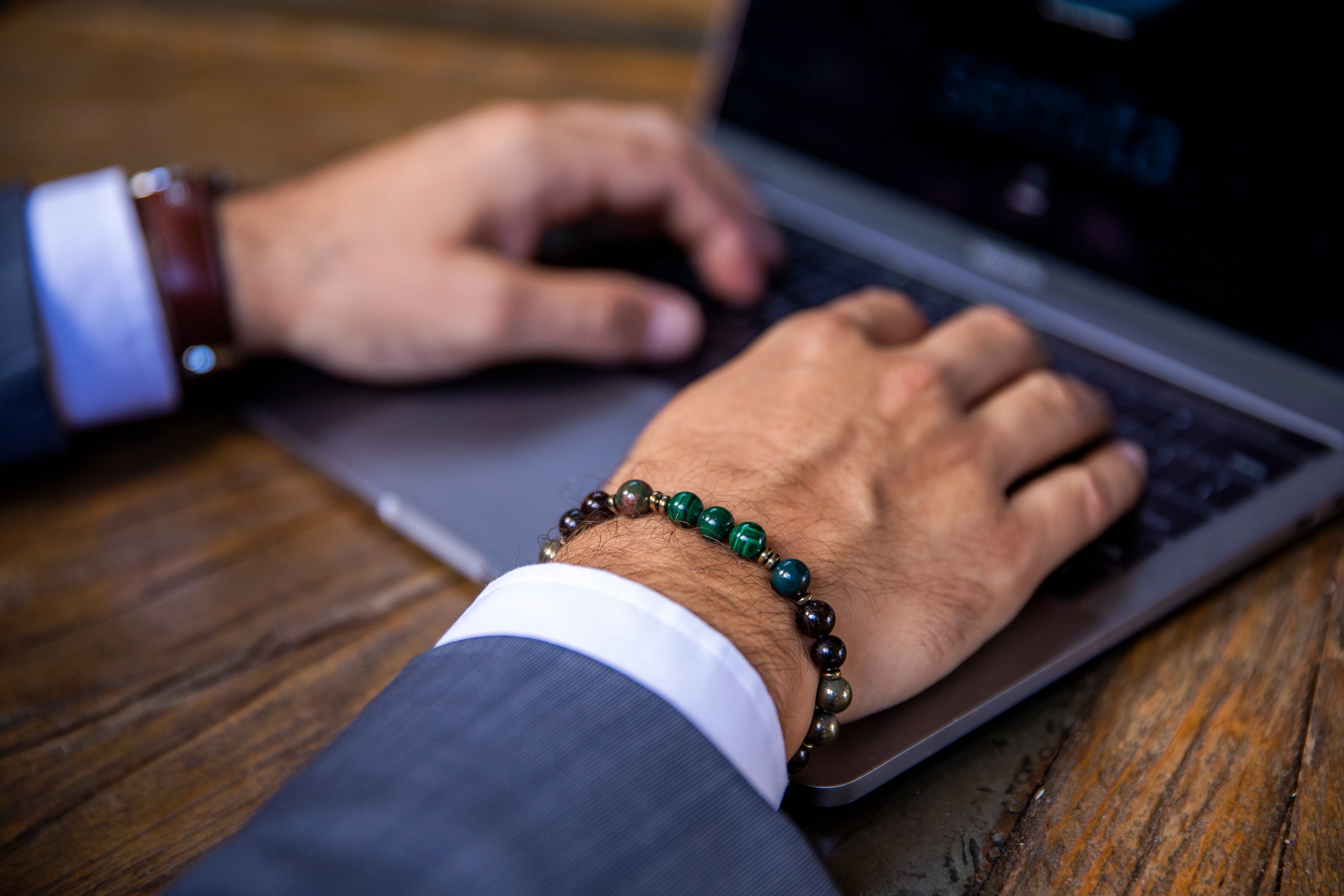 Men wearing fortune and luck bracelet using laptop